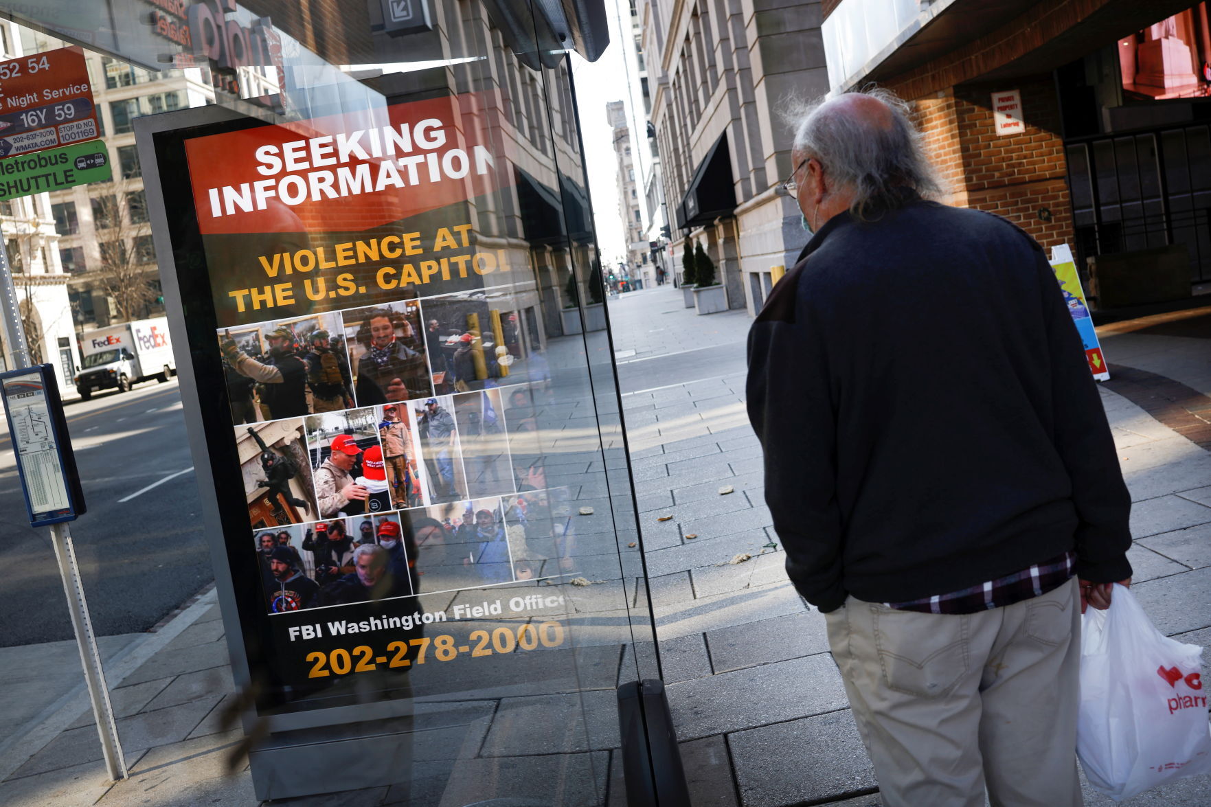 A local resident looks at a billboard with pictures of supporters of U.S. President Donald Trump wanted by the FBI who participated in storming the U.S. Capitol, forcing Congress to postpone a session certifying the results of the 2020 U.S. presidential el